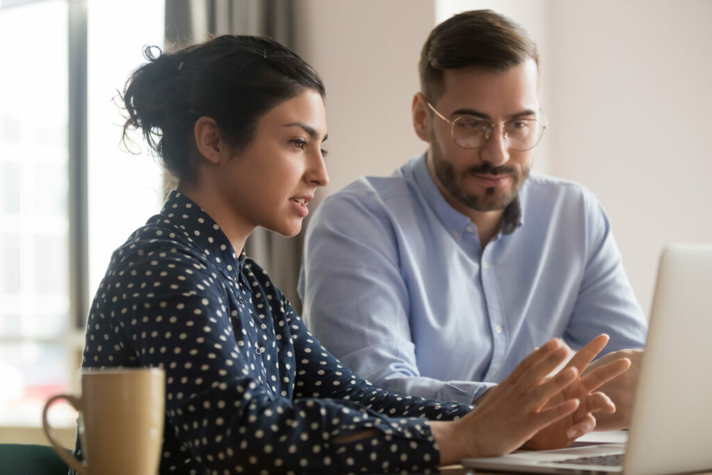 A man and women talking and looking at a laptop screen