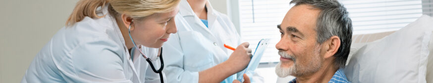 Doctor listening to patient's heartbeat while nurse takes note.