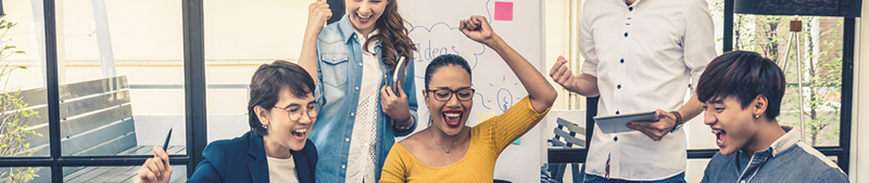 Group of diverse colleagues cheering and celebrating at a meeting table