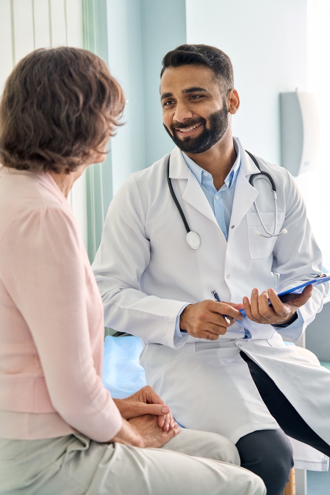 Young happy medical worker speaking with a patient