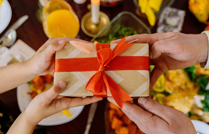 Wrapped box with a red ribbon being passed from one to another