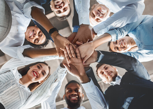 Group of diverse professionals with all hands in to represent teamwork